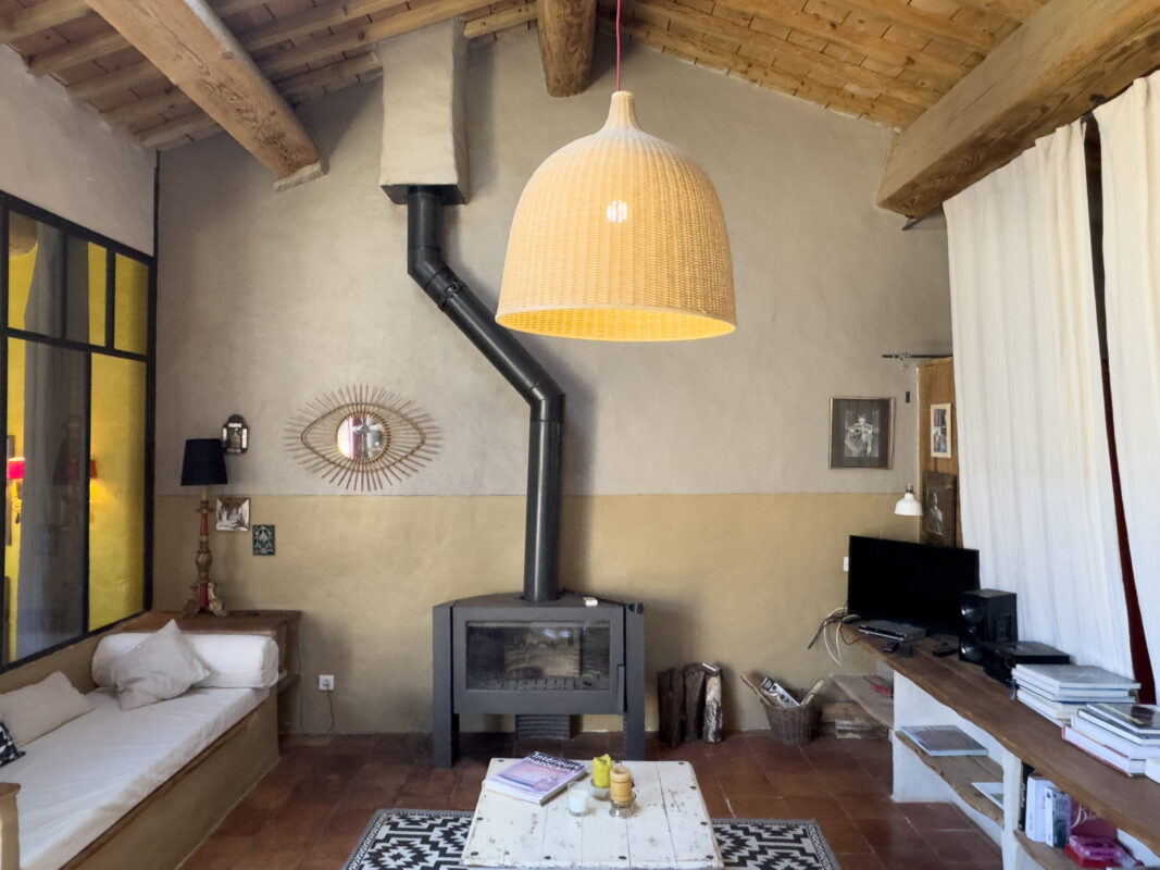 Salon chaleureux avec poêle à bois, mobilier rustique et décoration moderne, dans le loft écologique de Villesèque-des-Corbières.